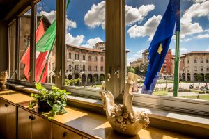 Vista sulla piazza dall'interno di una sala con bandiere fuori dalla finestra.