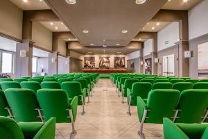 Interno dell'auditorium Ricci. Sala con sedie verdi.